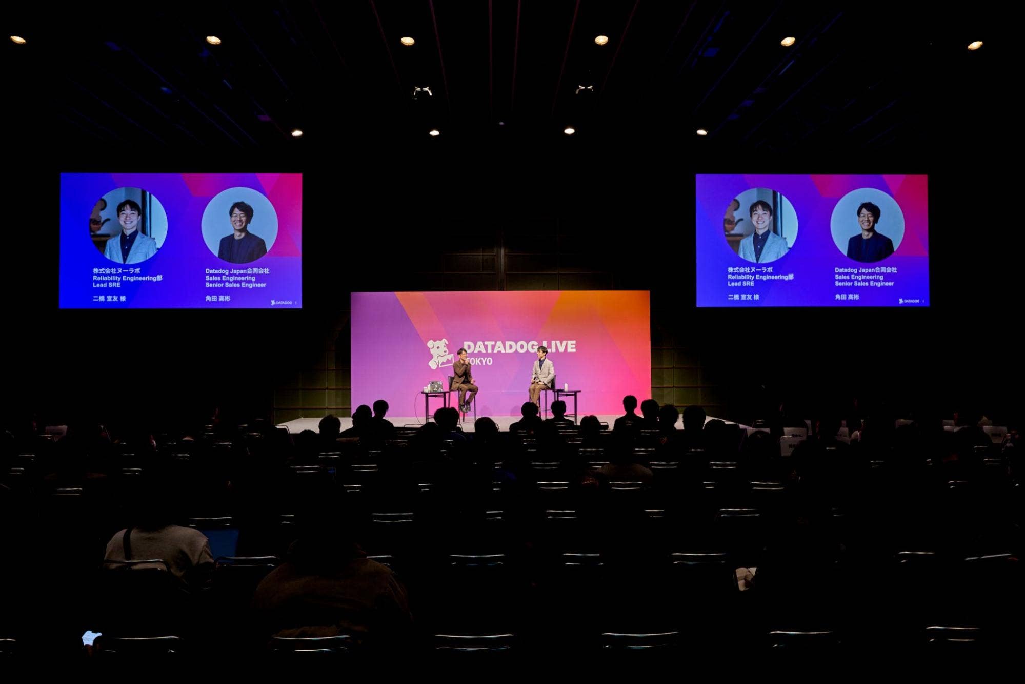 Datadog Live Tokyo 2025 のステージで、観客の前に登壇者が着席し対談を行っている様子。