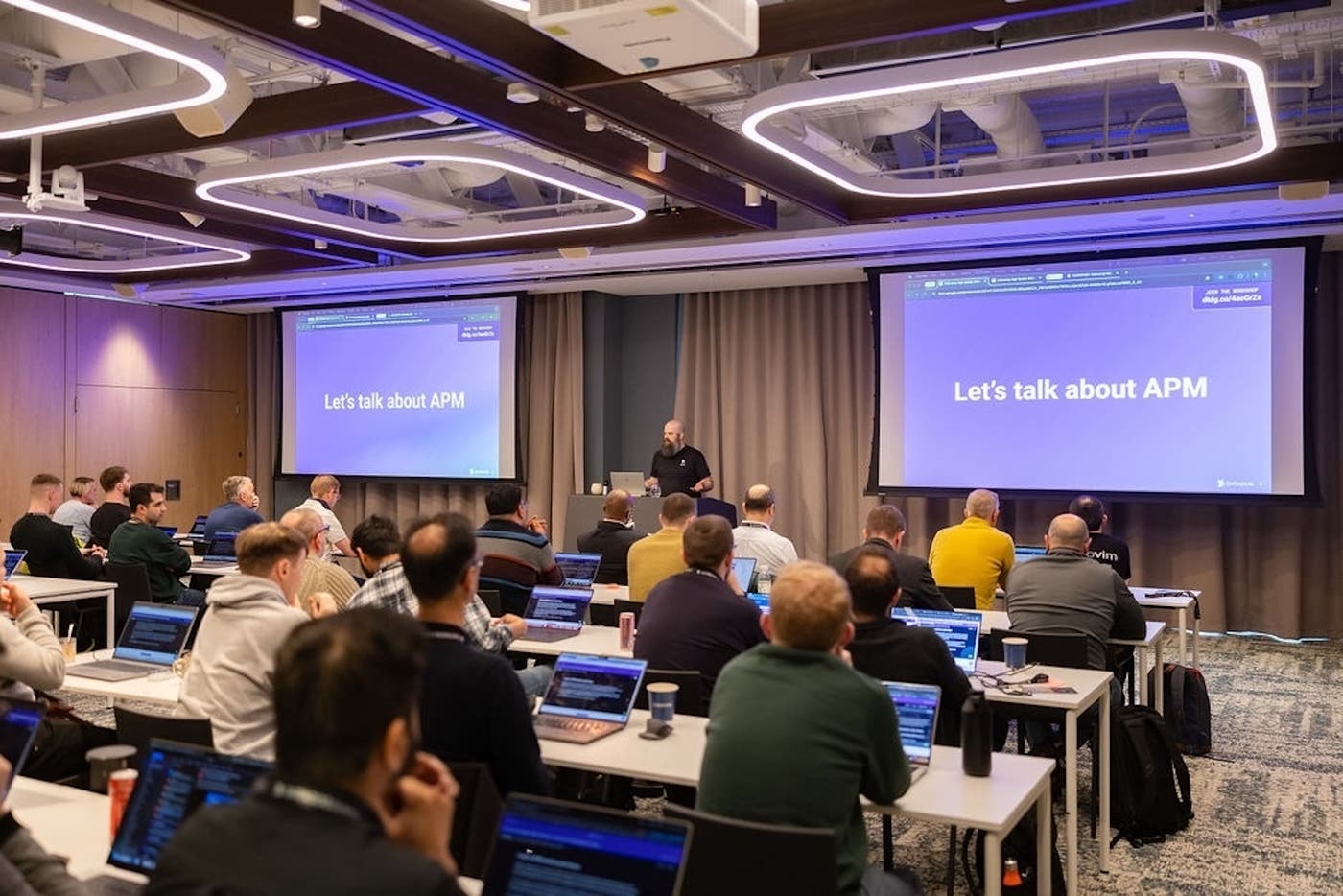 A presenter leads a workshop in a room full of attendees at Datadog Summit. A presenter leads a workshop in a room full of attendees at Datadog Summit.