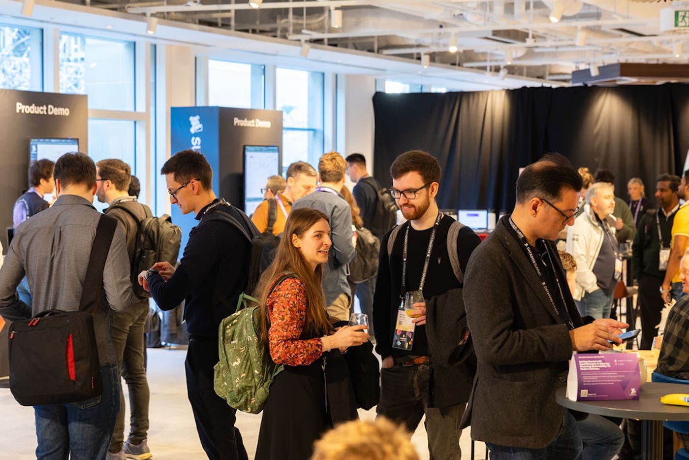 Small groups of attendees chat with each other near the area for product demos. Small groups of attendees chat with each other near the area for product demos.