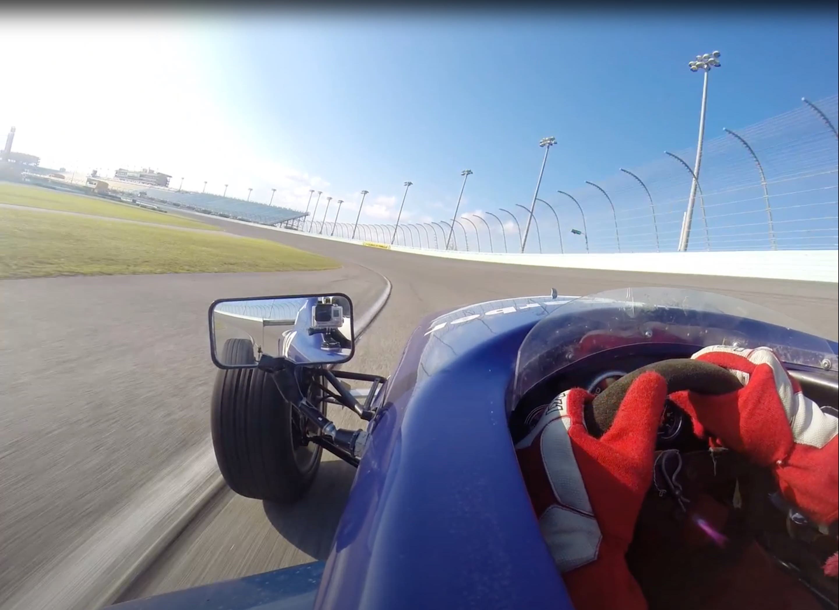Photograph looking out of a race car, with a view of the track and of the side mirror. Photograph looking out of a race car, with a view of the track and of the side mirror.